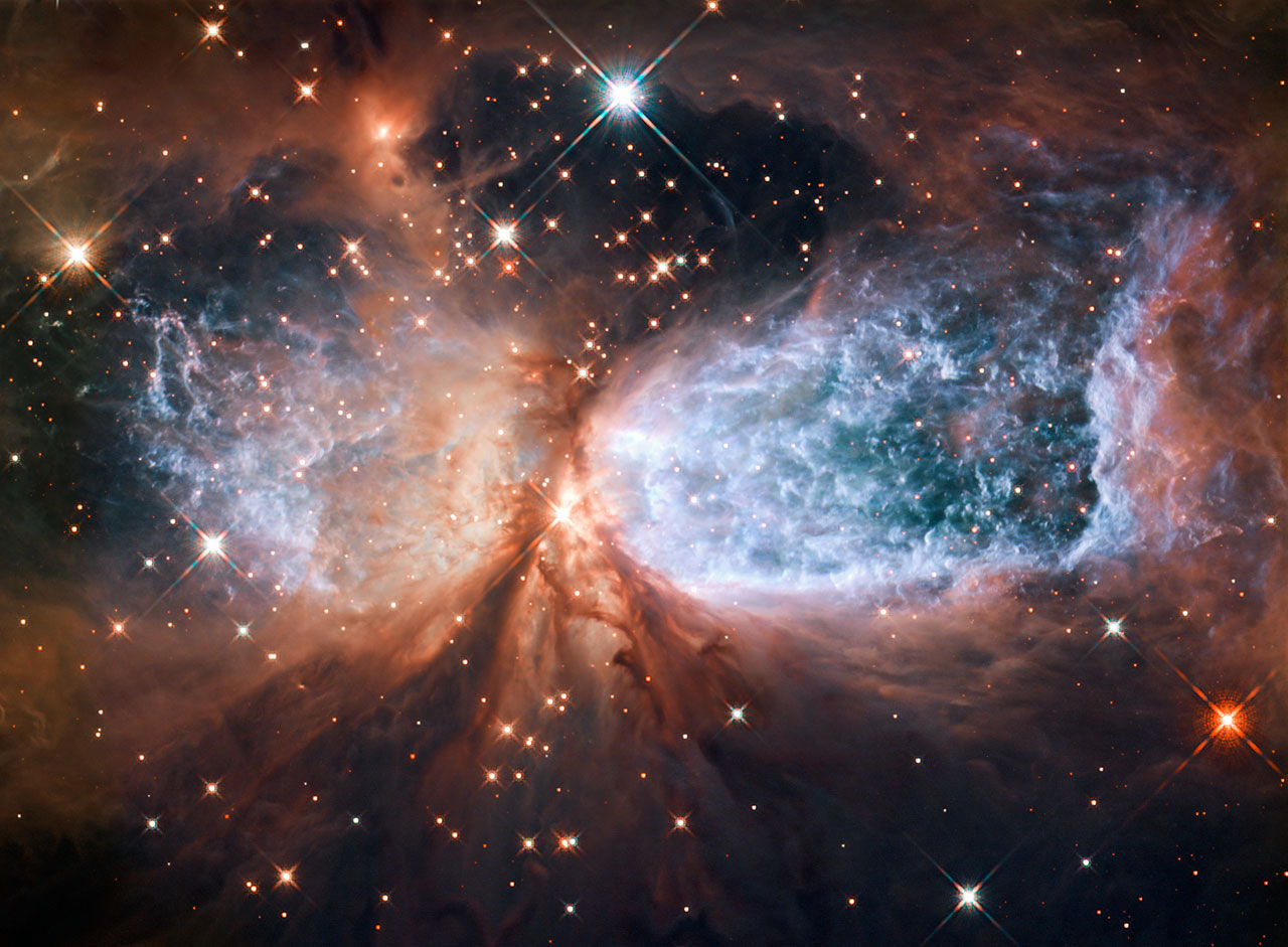 This image from the NASA/ESA Hubble Space Telescope shows Sh 2-106, or S106 for short. This is a compact star forming region in the constellation Cygnus (The Swan). A newly-formed star called S106 IR is shrouded in dust at the centre of the image, and is responsible for the surrounding gas cloud’s hourglass-like shape and the turbulence visible within. Light from glowing hydrogen is coloured blue in this image.