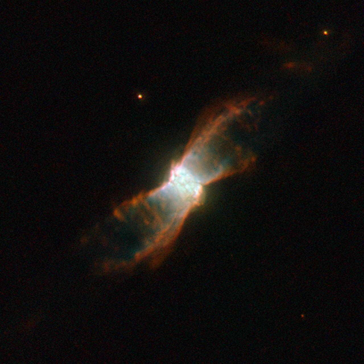 The breathtaking butterfly-like planetary nebula NGC 6881 is visible here in an image taken by the NASA/ESA Hubble Space Telescope. Located in the constellation of Cygnus, it is formed of an inner nebula, estimated to be about one fifth of a light-year across, and symmetrical “wings” that spread out about one light-year from one tip to the other. The symmetry could be due to a binary star at the nebula’s centre. NGC 6881 has a dying star at its core which is about 60% of the mass of the Sun. It is an example of a quadrupolar planetary nebula, made from two pairs of bipolar lobes pointing in different directions, and consisting of four pairs of flat rings. There are also three rings in the centre. A planetary nebula is a cloud of ionised gas, emitting light of various colours. It typically forms when a dying star — a red giant — throws off its outer layers, because of pulsations and strong stellar winds. The star’s exposed hot, luminous core starts emitting ultraviolet radiation, exciting the outer layers of the star, which then become a newly born planetary nebula. At some point, the nebula is bound to dissolve in space, leaving the central star as a white dwarf — the final evolutionary state of stars. The name “planetary” dates back to the 18th century, when such nebulae were first discovered — and when viewed through small optical telescopes, they looked a lot like giant planets. Planetary nebulae usually live for a few tens of thousands of years, a short phase in the lifetime of a star. The image was taken through three filters which isolate the specific wavelength of light emitted by nitrogen (shown in red), hydrogen (shown in green) and oxygen (shown in blue).