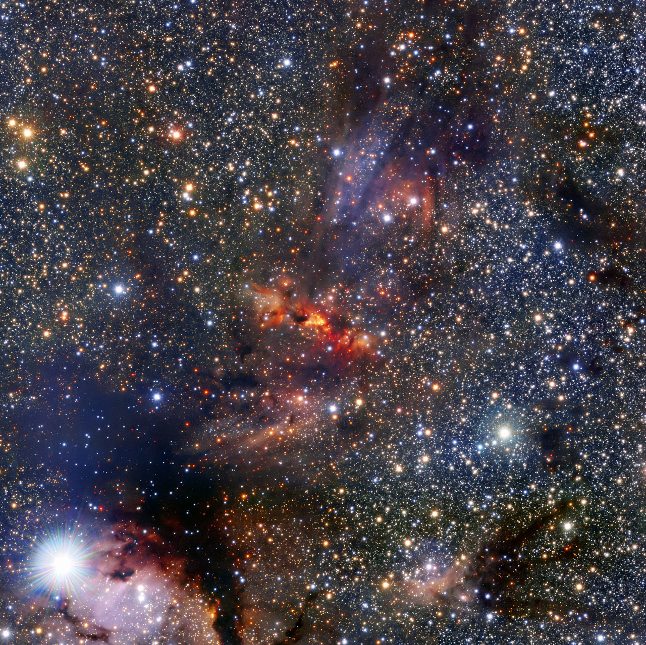 This image shows a region of the Milky Way that lies within the constellation of Scorpius, close to the central plane of the galaxy. The region hosts a dense cloud of dust and gas associated with the molecular cloud IRAS 16562-3959, clearly visible as an orange smudge among the rich pool of stars at the centre of the image. Clouds like these are breeding grounds for new stars. In the centre of this cloud the bright object known as G345.4938+01.4677 can just be seen beyond the veil of gas and dust. This is a very young star in the process of forming as the cloud collapses under gravity. The young star is very bright and heavy —  roughly 15 times more massive than the Sun — and featured in a recent Atacama Large Millimeter/submillimeter Array (ALMA) result. The team of astronomers made surprising discoveries within G345.4938+01.4677 — there is a large disc of gas and dust around the forming star as well as a stream of material flowing out from it. Theories predict that neither such a stream, nor the disc itself, are likely to exist around stars like G345.4938+01.4677 because the strong radiation from such massive new stars is thought to push material away. This image was made using the Visible and Infrared Survey Telescope for Astronomy (VISTA), which is part of ESO’s Paranal Observatory in the Atacama Desert of Chile. It is the world’s largest survey telescope, with a main mirror that measures over four metres across. The colour image was produced by the VVV survey, which is one of six large public surveys that are devoted to mapping the southern sky. The bright star in the bottom left of the image is known as HD 153220.
