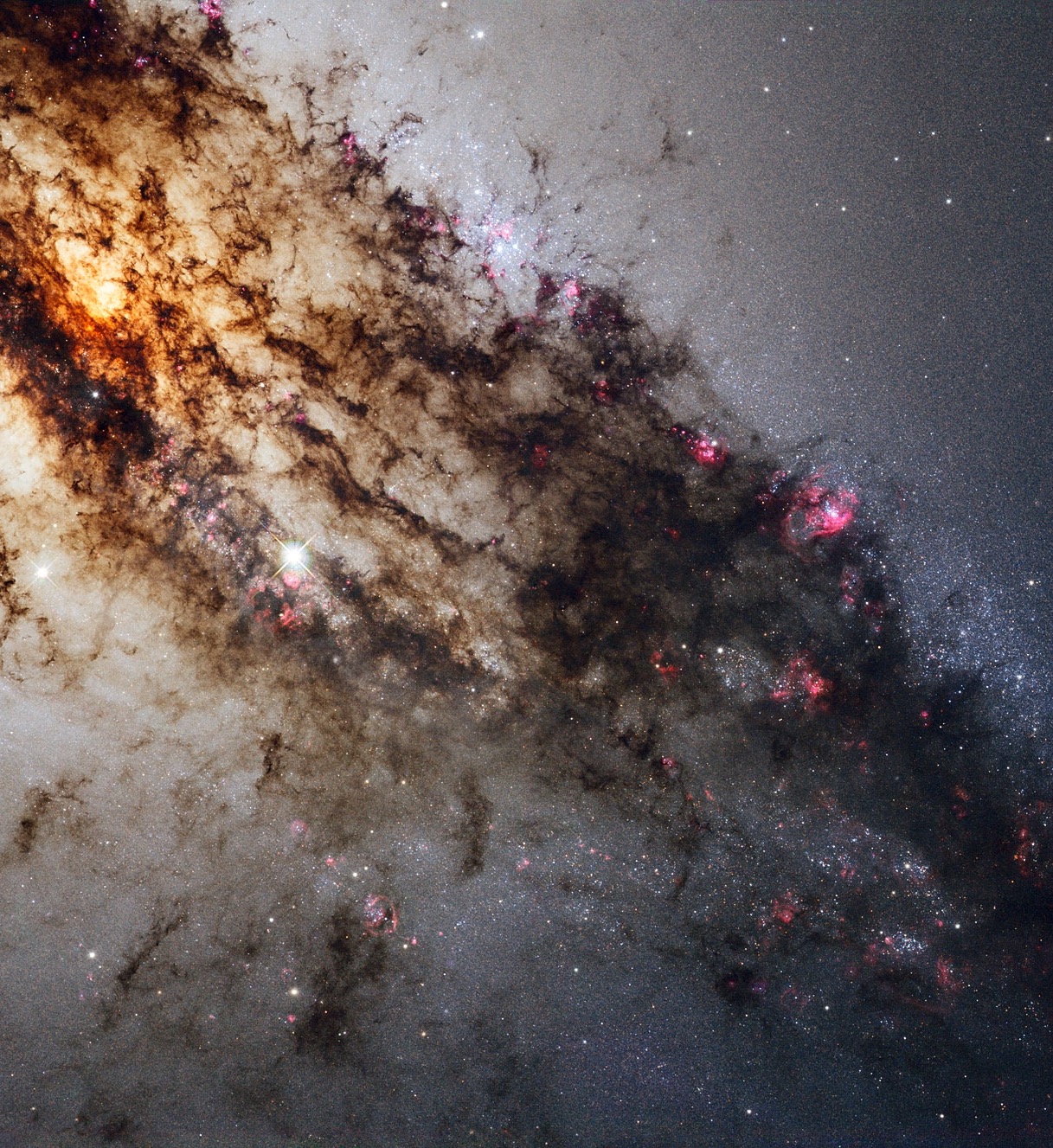 Centaurus A, also known as NGC 5128, is well known for its dramatic dusty lanes of dark material. Hubble’s new observations, using its most advanced instrument, the Wide Field Camera 3, are the most detailed ever made of this galaxy. They have been combined here in a multi-wavelength image which reveals never-before-seen detail in the dusty portion of the galaxy. As well as features in the visible spectrum, this composite shows ultraviolet light, which comes from young stars, and near-infrared light, which lets us glimpse some of the detail otherwise obscured by the dust.