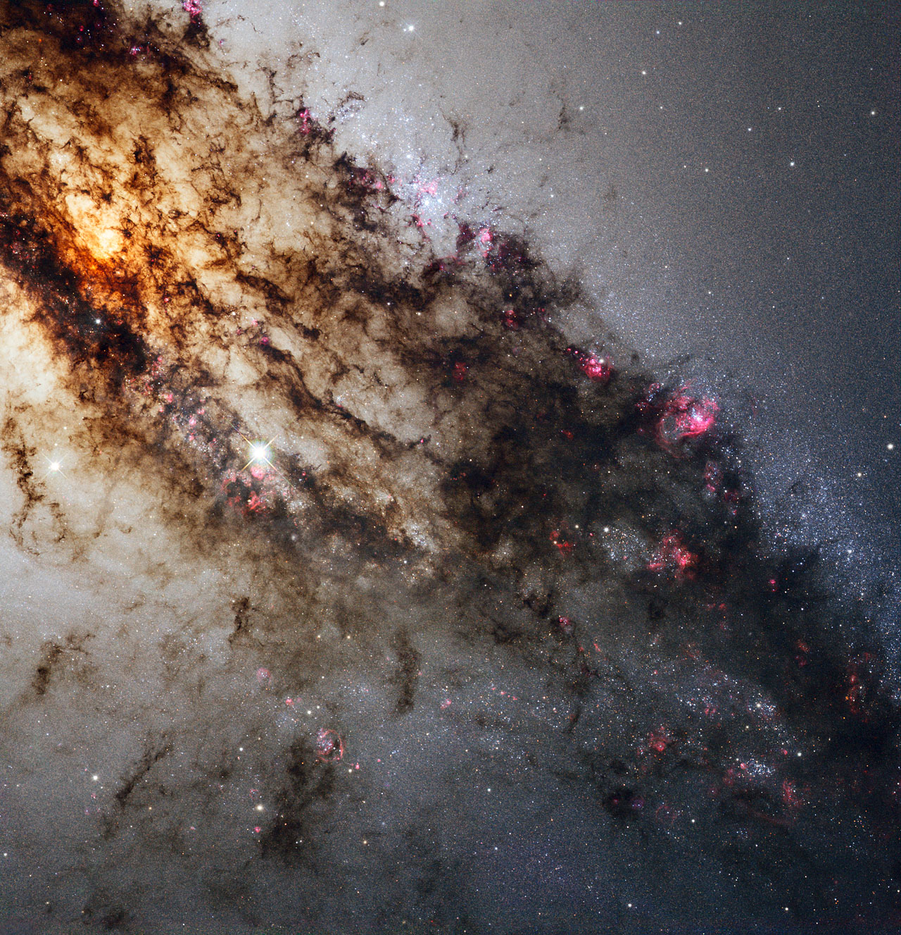Centaurus A, also known as NGC 5128, is well known for its dramatic dusty lanes of dark material. Hubble’s new observations, using its most advanced instrument, the Wide Field Camera 3, are the most detailed ever made of this galaxy. They have been combined here in a multi-wavelength image which reveals never-before-seen detail in the dusty portion of the galaxy. As well as features in the visible spectrum, this composite shows ultraviolet light, which comes from young stars, and near-infrared light, which lets us glimpse some of the detail otherwise obscured by the dust.