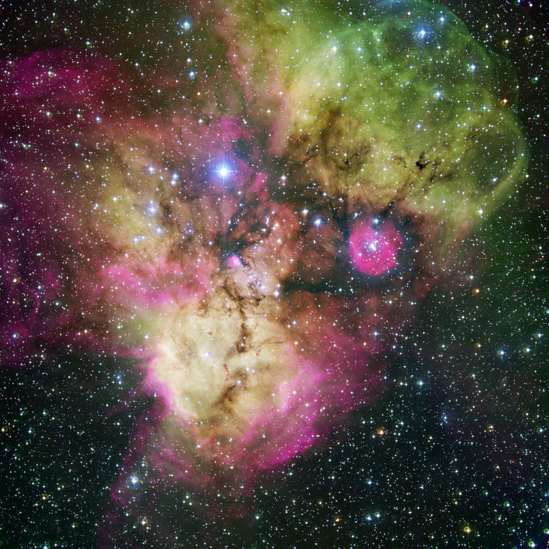 Area surrounding the stellar cluster NGC 2467, located in the southern constellation of Puppis ("The Stern"). With an age of a few million years at most, it is a very active stellar nursery, where new stars are born continuously from large clouds of dust and gas. The image, looking like a colourful cosmic ghost or a gigantic celestial Mandrill, contains the open clusters Haffner 18 (centre) and Haffner 19 (middle right: it is located inside the smaller pink region — the lower eye of the Mandrill), as well as vast areas of ionised gas. The bright star at the centre of the largest pink region on the bottom of the image is HD 64315, a massive young star that is helping shaping the structure of the whole nebular region. This image is available as a mounted image in the ESOshop. #L