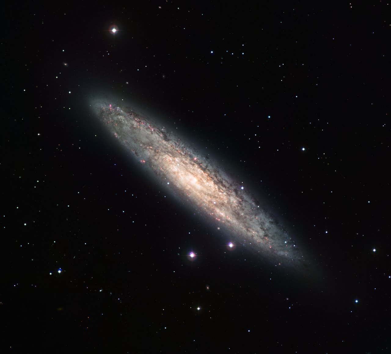 Measuring 70 000 light-years across and laying 13 million light-years away, the nearly edge-on spiral galaxy NGC 253 is revealed here in an image from the Wide Field Imager (WFI) on the MPG/ESO 2.2-metre telescope at the La Silla Observatory. The image is based on data obtained through four different filters (R, V, H-alpha and OIII). North is up and East to the left. The field of view is 30 arcminutes.