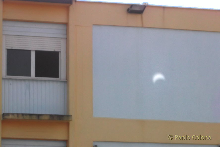 Il Sole in eclissi parziale proiettato sul muro di una scuola con uno specchietto